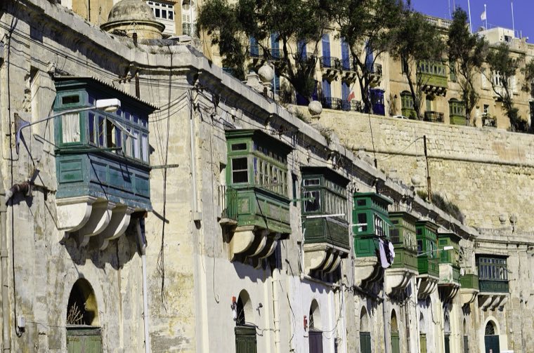 Green wooden balconies along a limestone street in Valletta