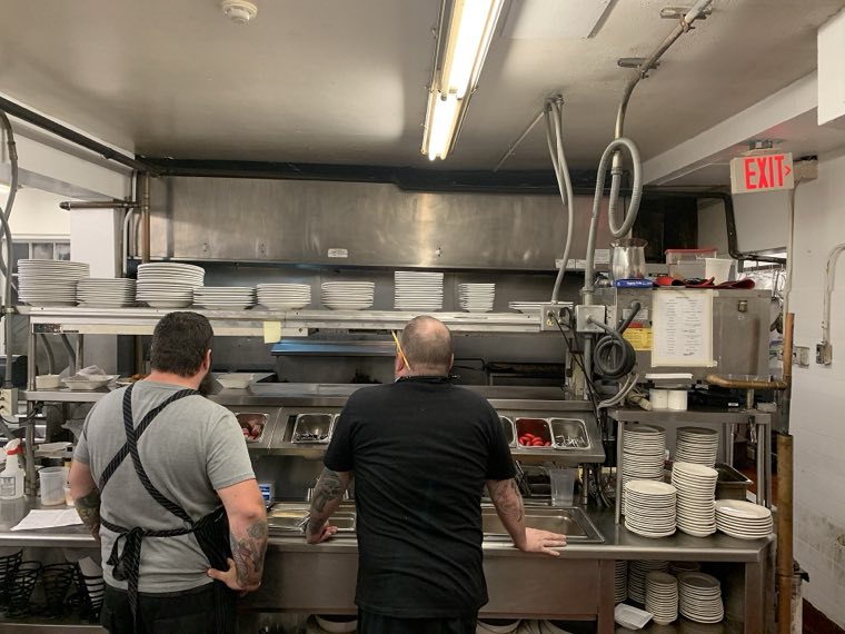 Chefs at the pass of a stainless steel restaurant kitchen